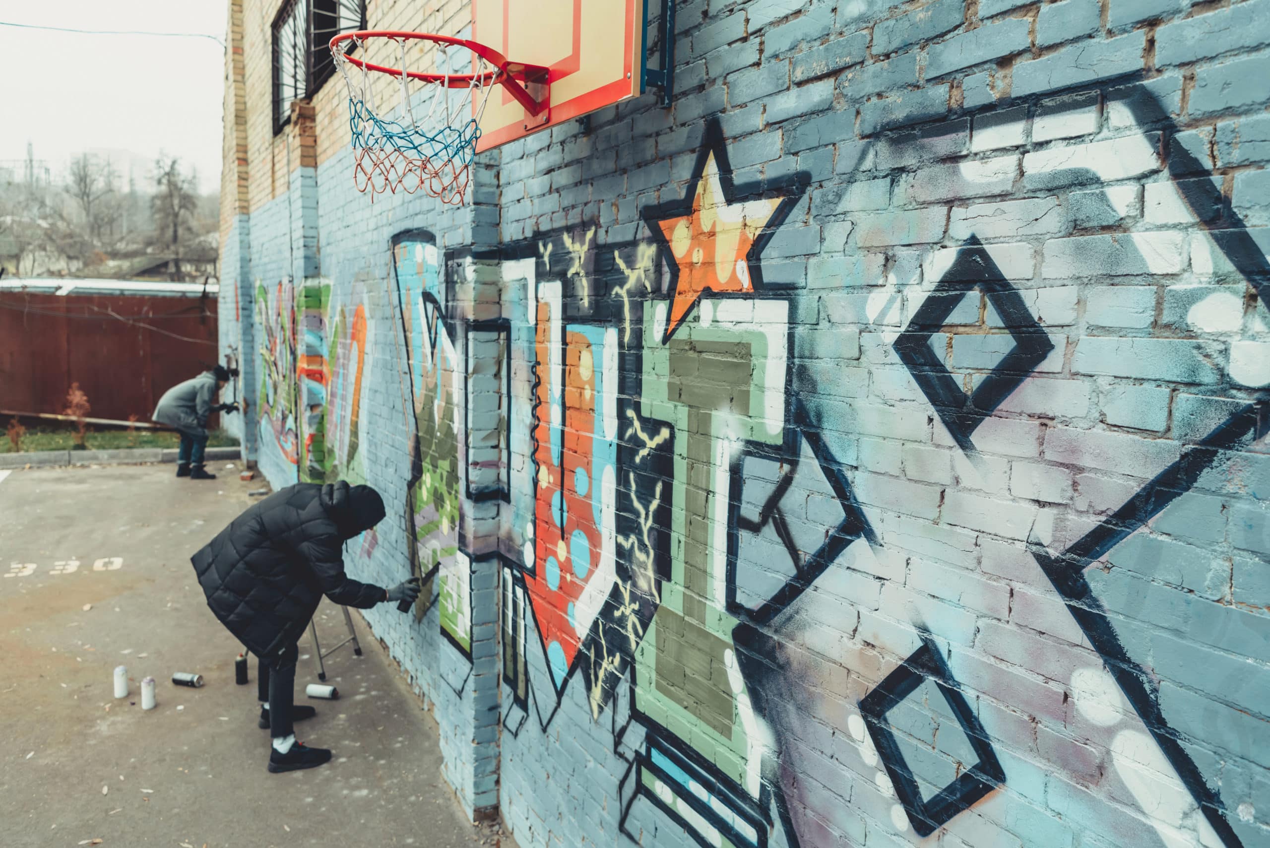 male street artist painting colorful graffiti on wall