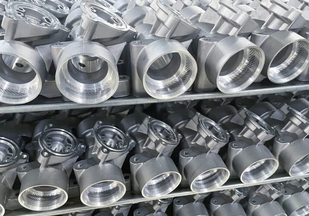 batch of machined die cast aluminum parts placed on a rack, automotive parts mass production, CNC machining, mass production of die casting parts, mass production batch of machined die cast aluminum parts placed on a rack, automotive parts mass production, CNC machining, mass production of die casting parts, aluminum die cast parts mass production